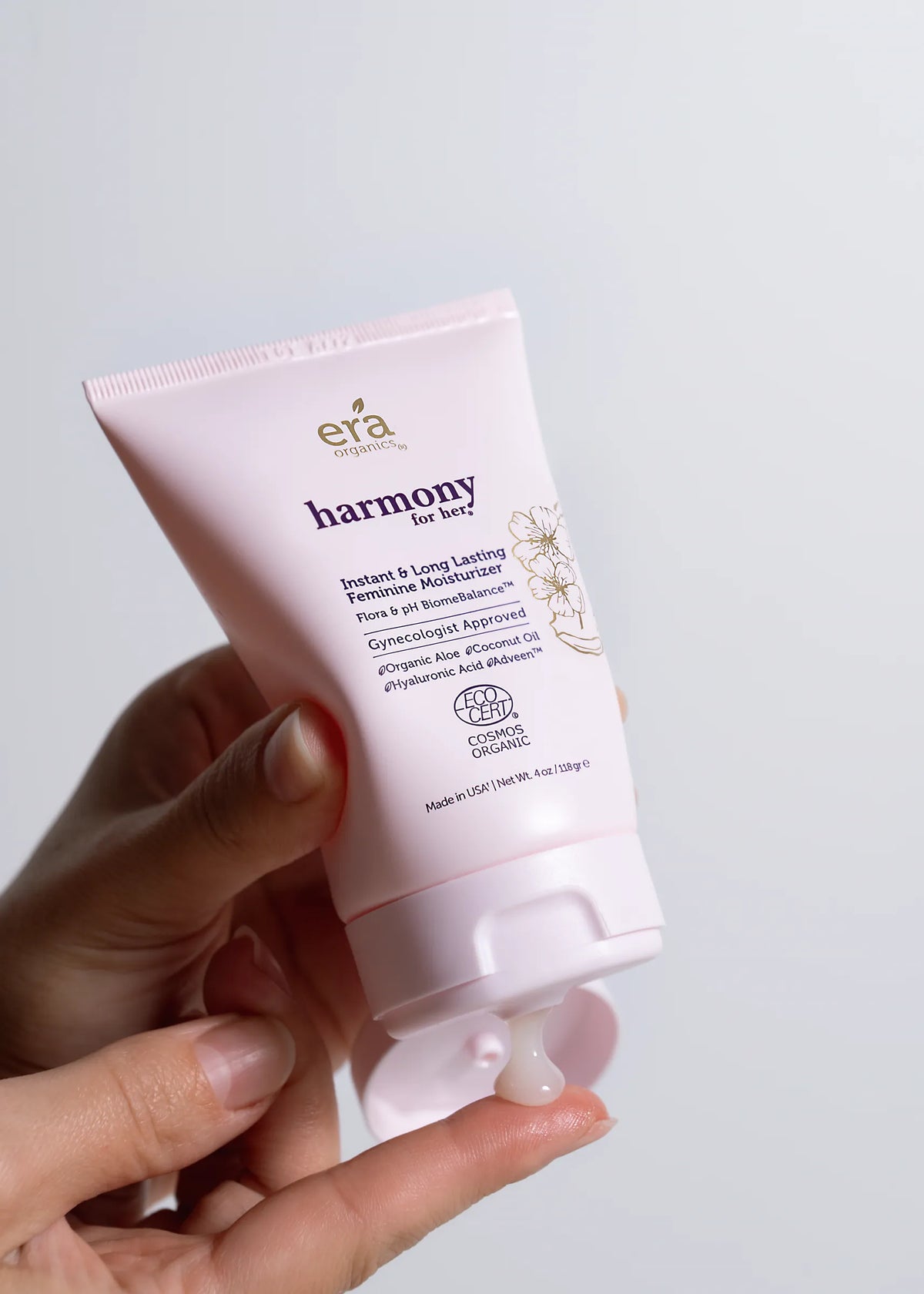 A hand squeezing a tube of Era Organics Harmony vaginal moisturizer