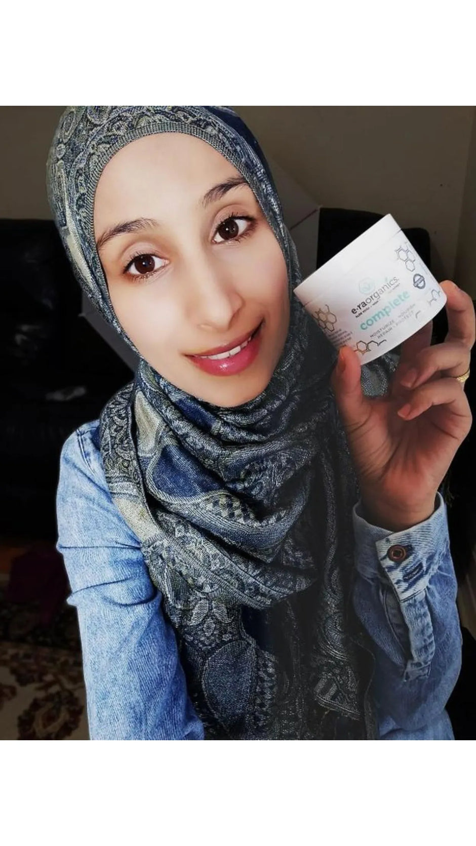 Smiling woman in a headscarf holding a jar of Complete+
