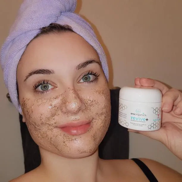 Woman in a hair towel wearing the Revive+ mask and holding the jar