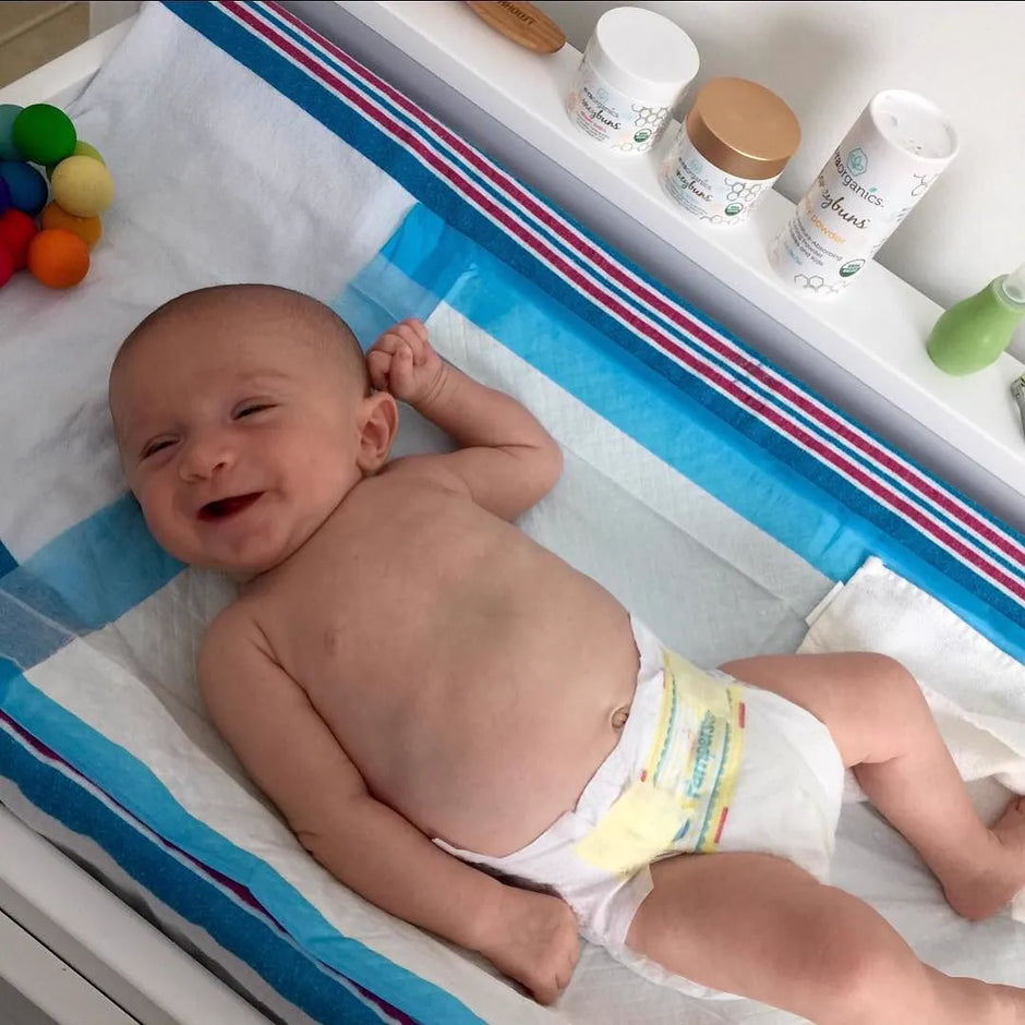 Smiling baby on a changing table with Era products on the shelf