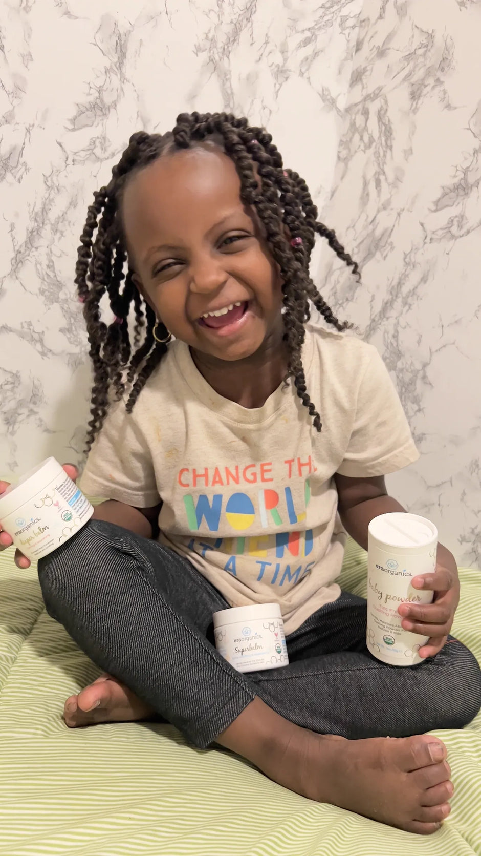 Laughing child sitting with jars of Superbalm